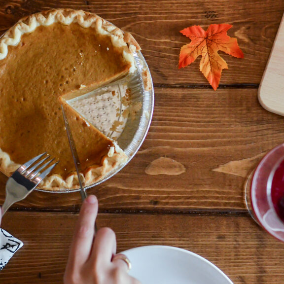 person-holding-table-knife-about-to-slice-pumpkin-pie